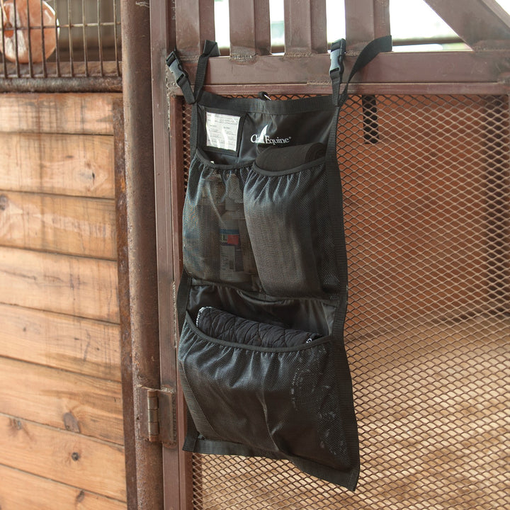 Classic Equine stall front grooming bag with multiple compartments and clips for organizing grooming tools in a barn or stable.